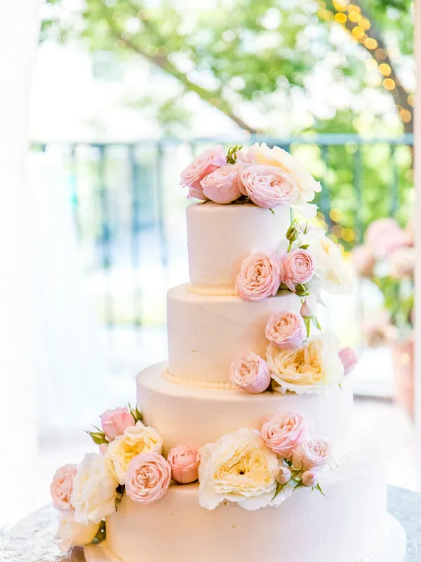 A tiered white wedding cake decorated with fresh roses