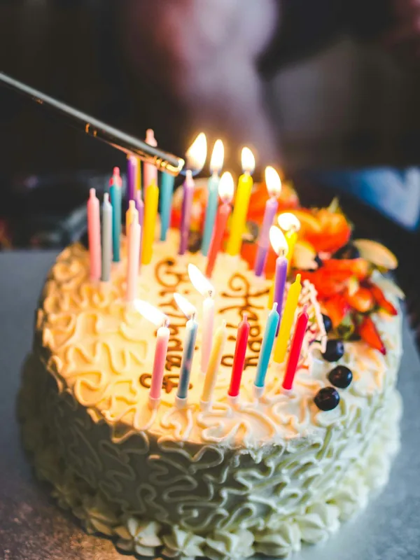 Candles being lit on a frosted birthday cake