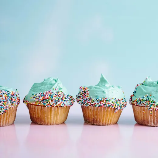 A row of cupcakes with mint frosting and sprinkles